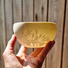 Load image into Gallery viewer, Translucent porcelain bowl with an Agapanthus flower design etched onto the inside, held in my hand, seen from the outside so the soft silhouette is visable.
