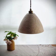 Load image into Gallery viewer, Cream unlit Porcelain Lampshade etched with swirling Jasmine design. Yellow vase with flowers in the background.