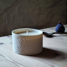 Load image into Gallery viewer, Birds Foot Trefoil foliage etched into a Porcelain Candle Pot, lit by daylight. rustic lifestyle shot.