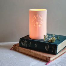 Load image into Gallery viewer, Porcelain tealight beaker with Agapanthus design displayed on books. 
