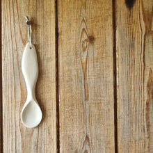 Load image into Gallery viewer, Sculpted porcelain spoon hanging on a wooden door.
