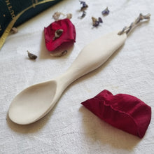 Load image into Gallery viewer, Sculpted porcelain spoon on a white tablecloth with red petals.
