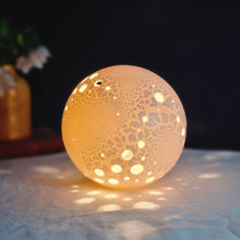 Load image into Gallery viewer, Porcelain Lamp with textured surface and round holes casting lightspots around it.
