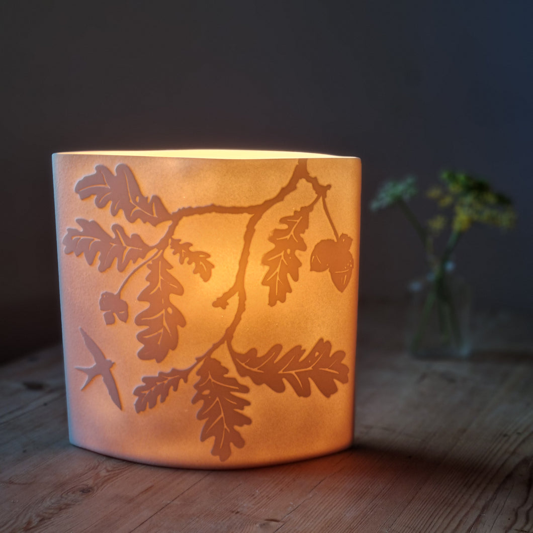 Oak tree-inspired porcelain ellipse lamp, featuring intricate etchings of oak leaves and branches, radiating a warm, nature-infused glow.