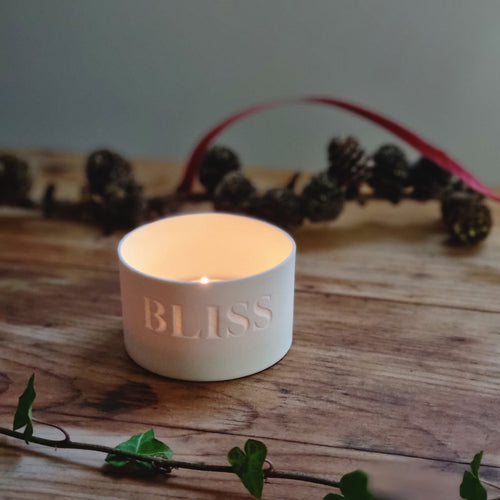 Creamy white porcelain tealight holder with thwe word BLISS etched into it.
