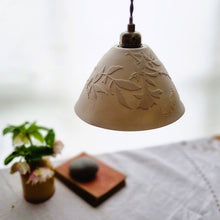 Load image into Gallery viewer, Creamy white porcelain Lampshade etched with wild roses and a butterfly. A vase with flowers, a book and a pebble in the background.
