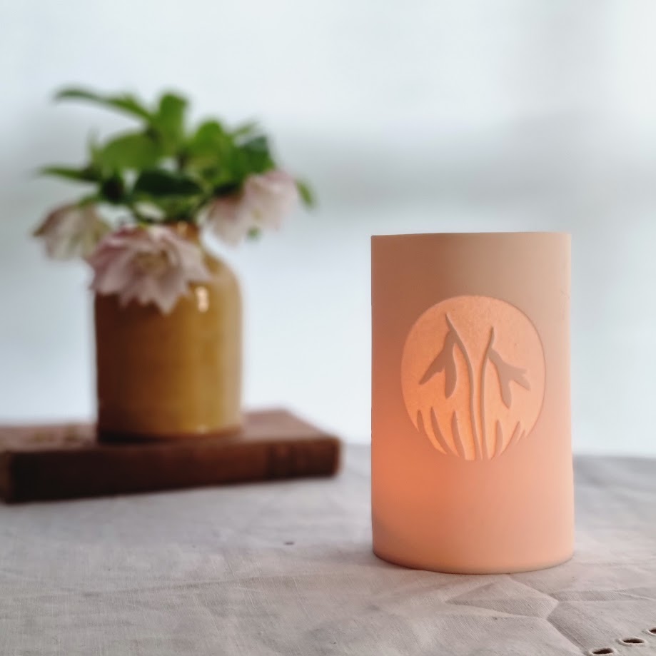 Porcelain Beaker with etched circular Snowdrop design. Glowing gently.