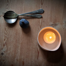 Load image into Gallery viewer, Porcelain Tealight pot etched with single Daisy, gently glowing, seen from above. Fig and cutlery on the left.
