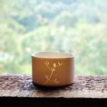 Load image into Gallery viewer, Birds Foot Trefoil foliage etched into a Porcelain Candle Pot, on the windowsill, lit by daylight.
