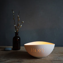 Load image into Gallery viewer, Porcelain bowl lit with a candle with HOPE etched into it, pebble and bottle with pussy willow on the left.
