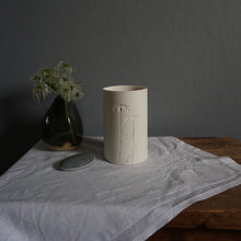 Load image into Gallery viewer, Porcelain Beaker with Two Daisies etched into it on white table cloth with green vase and pebble to the left
