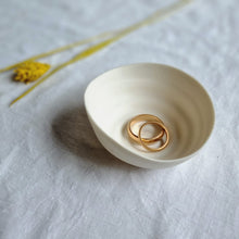 Load image into Gallery viewer, Creamy white porcelain spiral bowl with two gold rings in it.
