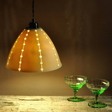 Load image into Gallery viewer, Orange glowing bell shaped lampshade with lines of brighter dots running top to bottom. two vintage green stem glasses on the right.
